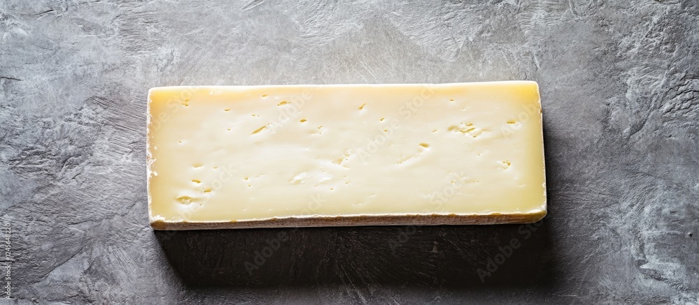 Poster Minimalist block of cheese positioned centrally on a textured gray slate background emphasizing simplicity and culinary creativity in food photography