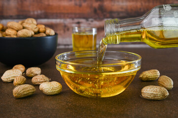 Pouring peanut oil also called as groundnut oil in a cup.
