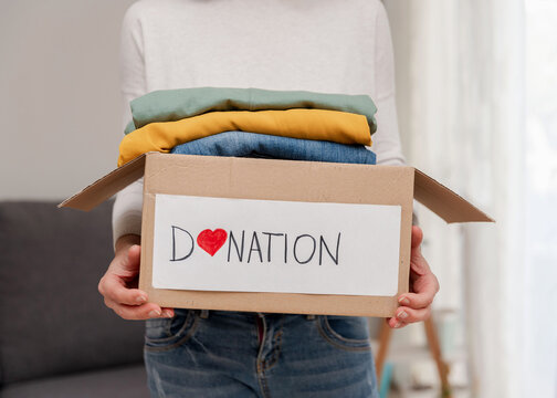 Close up of person holding donation box with used clothes for charity organization