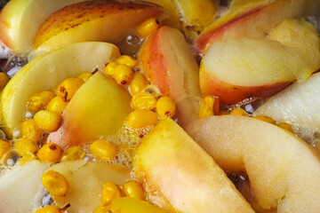 Boiling compote cooked of apples and seabukthorn.