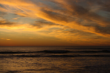 Obraz premium Sunset at sea with high, reddish clouds.