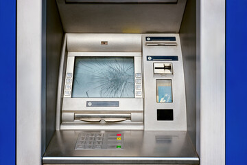 A broken ATM on a city street with a broken screen.