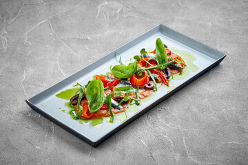 A vibrant and appetizing platter of marinated anchovies, served with fresh vegetables and herbs.