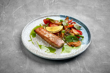 A close-up of a grilled salmon, showcasing the tender texture of the meat and the crispy exterior. The dish is served with roasted vegetables, creating a delightful contrast of textures