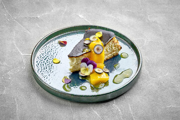 A slice of Basque burnt cheesecake, topped with fresh fruit and edible flowers.