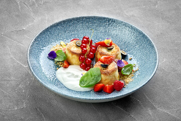 A vibrant and appetizing plate of Ukrainian syrniki, topped with fresh berries and a drizzle of sweet sauce.