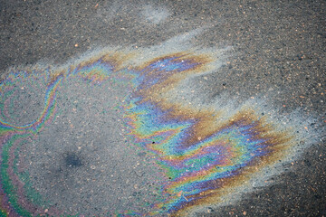 Obraz premium Iridescent oil spill forms vibrant rainbow patterns on rough asphalt surface
