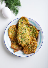 Zucchini fritters with dill on a white background