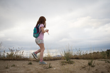  girl, hiking field with backpack. child backpacker walking in nature. Summer. Horizontal
