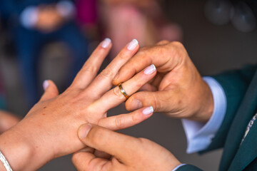 Groom placing wedding ring on bride's finger during ceremony