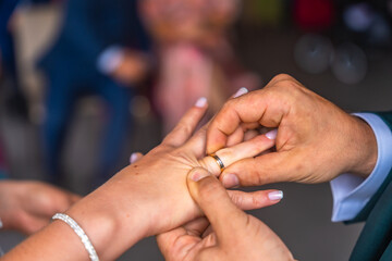 Groom placing wedding ring on bride's finger during ceremony