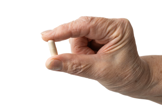 Senior female hand holding one white medicine capsule, antibiotic pills, vitamins, or painkillers, isolated on a transparent background. Healthcare and treatment concept