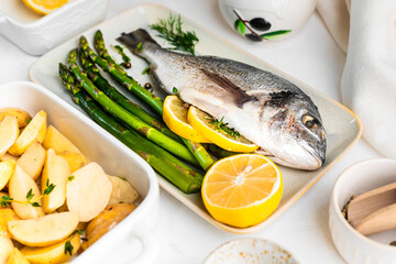he concept of a delicious dinner. raw dorado fish with asparagus, lemon and potatoes
