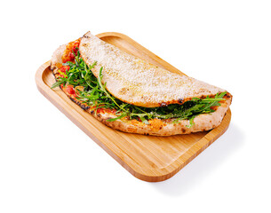 Delicious flatbread sandwich filled with fresh greens and toppings served on a wooden tray