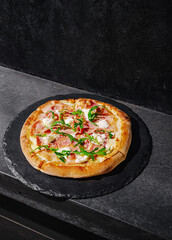 Delicious pizza topped with fresh ingredients on a dark stone surface in a modern kitchen setting