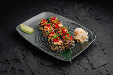 Sushi rolls presented on a dark plate with garnishes in an elegant restaurant setting