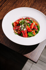 Fresh salad with vibrant vegetables and greens served in a white bowl on a wooden table