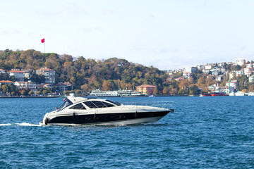 Obraz premium Luxury yacht sailing on the Bosphorus. Motor yacht on the blue sea. Watercraft idea concept. Horizontal photo. Landscape.