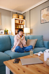 Woman having fever covered with blanket at home