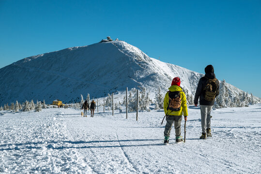Tourists in winter on a trail in the Karkonosze Mountains with Śnieżka