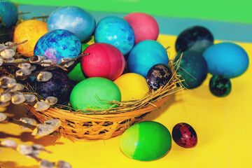 Colorful easter eggs in a basket on a yellow wooden table