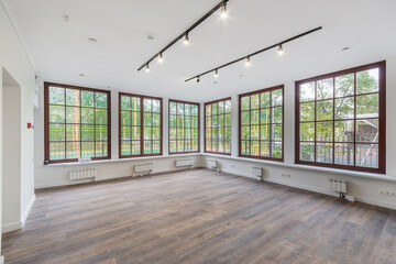 Panoramic windows in an empty spacious room with a final finish. Dark laminate, white walls. Unfurnished.