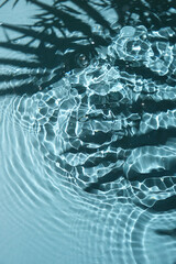 Blue water texture background on the noon sunlight with tropical leaves shadow.