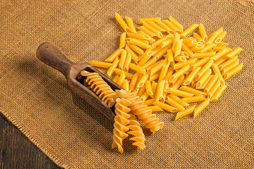 Penne and fusilli pasta on burlap fabric