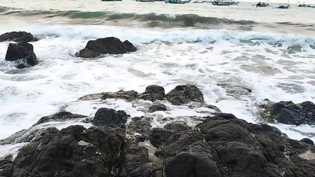 Footage of ocean waves motion splashing the beach rocks. Waves of water splashing on the gravel rocks at the sea banks, the beach coastlines. Clear water, high tidal wave. Nature view.
