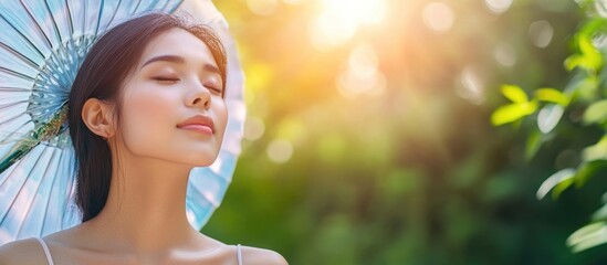 Fototapeta premium Woman relaxing outdoors with a sun umbrella during a warm summer day, serene expression and natural background, space for text or graphics.