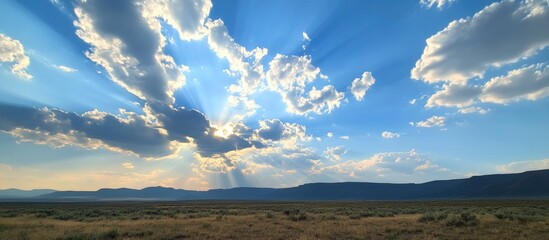 Scenic landscape featuring a vibrant blue sky with dramatic clouds and sun rays illuminating a serene horizon in nature.
