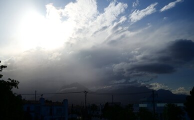 The sun is brightly shining through the stormy clouds in the sky