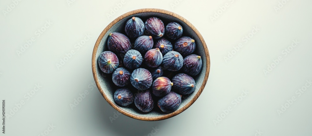 Poster bowl of fresh ripe figs displayed on a textured table surface in an elegant flat lay arrangement