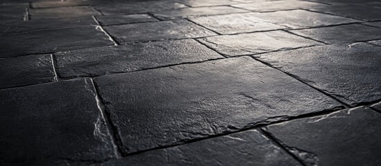 Textured black concrete outdoor surface with brick-like pattern highlighting natural light and shadows on the flooring.