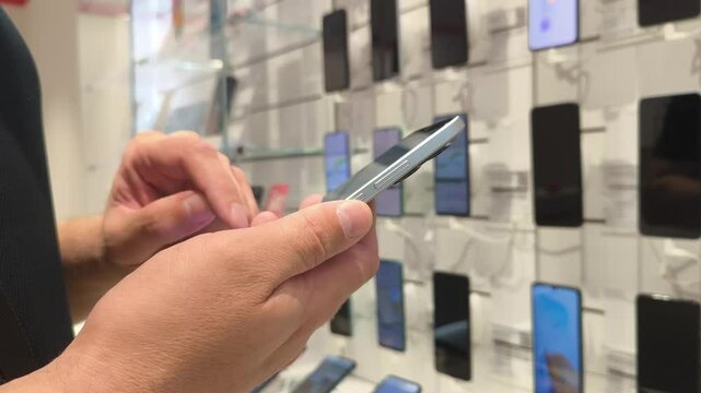 Choosing a phone in the store. Hand of male buyer testing smartphone in electronics store