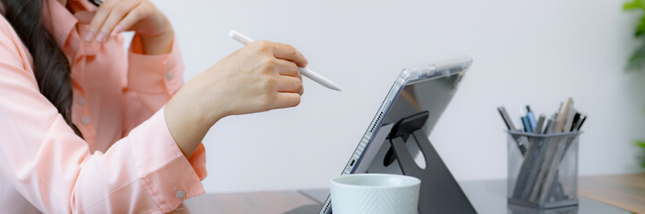 Close up hand holding stylus pen pointing on tablet reading digital data.