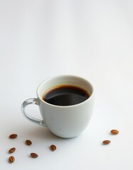Dark coffee served in a white cup with coffee beans scattered around on a light background
