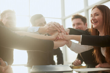 group of young business people joining their palms over a work Desk.