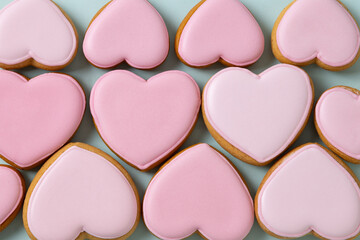 Homemade heart shaped glazed pink cookies as abstract pattern. Tasty treats for Valentine's day. View from above.
