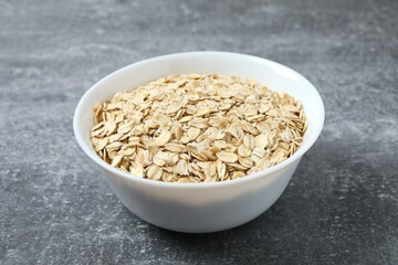 Composition with oatmeal flakes on gray background. Cooking breakfast