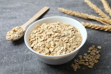 Composition with oatmeal flakes on gray background. Cooking breakfast