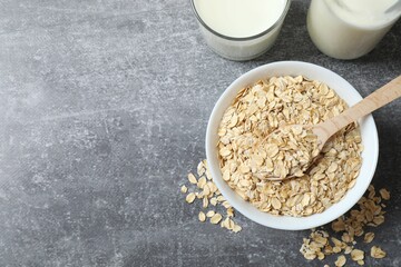 Composition with oatmeal flakes on gray background. Cooking breakfast