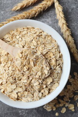Composition with oatmeal flakes on gray background. Cooking breakfast