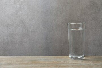 Glass with clear water on white table, space for text