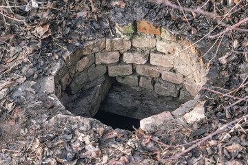 Fototapeta premium Old concrete sewer manhole with an open hatch without a lid.