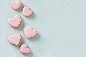 Seamless pattern of heart shaped cookies with pink glaze on blue background. Valentines day...