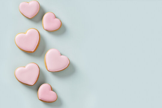 Fototapeta Seamless pattern of heart shaped cookies with pink glaze on blue background. Valentines day wallpaper or greeting card.