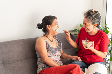 Women having fun applying clay mask at home