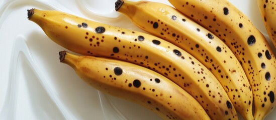 Ripe yellow bananas with black spots arranged on a white background showcasing fresh and healthy fruit options for culinary uses.