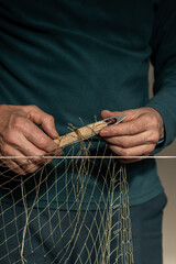 A senior  man prepares a fishing net for work